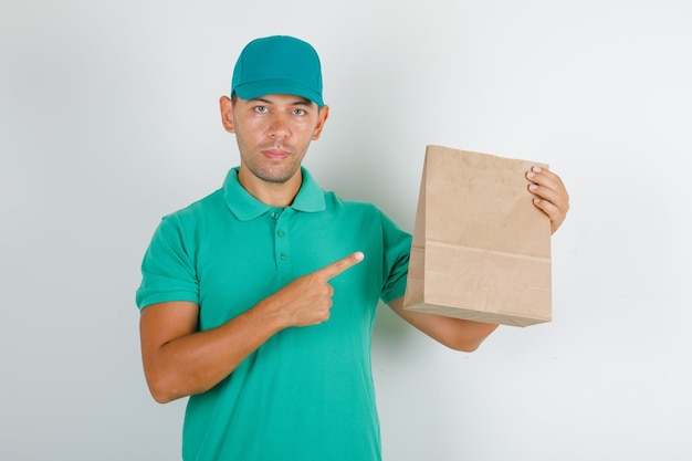 Repartidor mostrando bolsa de papel marrón en camiseta verde con gorra