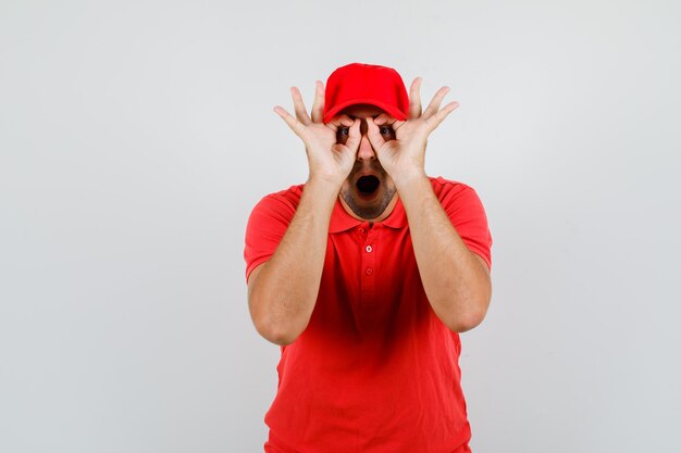 Repartidor mostrando gesto de gafas con la boca abierta en camiseta roja