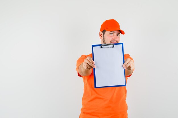 Repartidor mostrando portapapeles en camiseta naranja, gorra y mirando confiado, vista frontal.