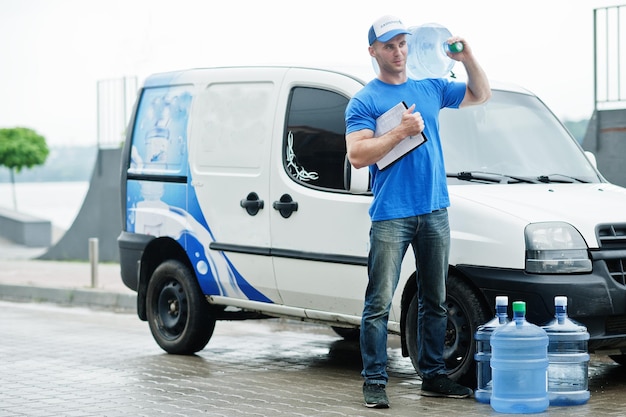 Repartidor con portapapeles en camioneta de carga delantera entregando botellas de agua