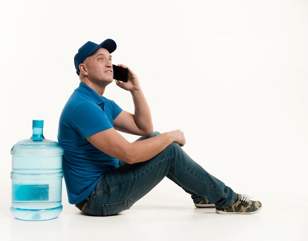 Repartidor posando con botella de agua y teléfono inteligente