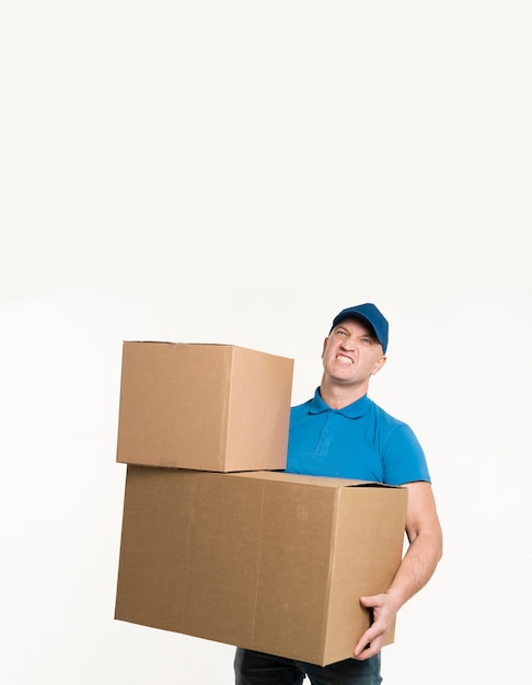 Repartidor posando mientras sostiene pesadas cajas de cartón