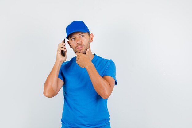 Repartidor con smartphone cerca de la oreja en camiseta azul