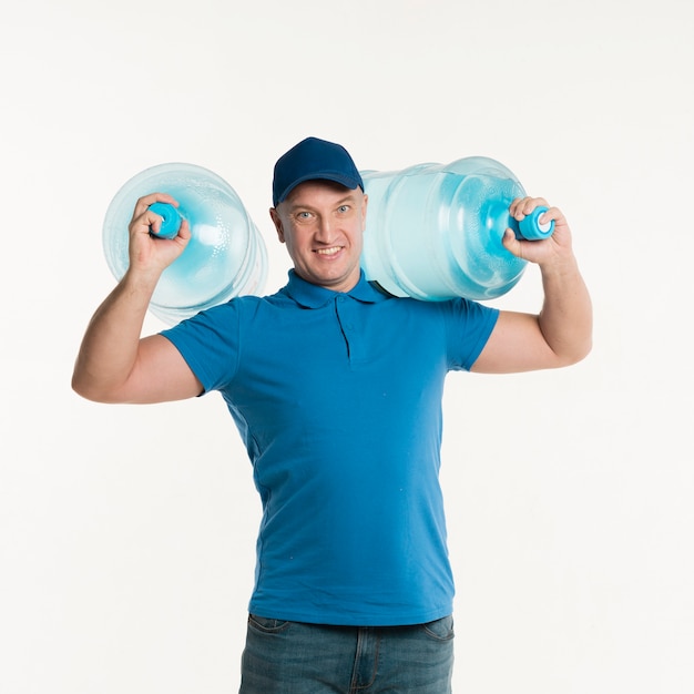 Repartidor sonriente llevando botellas de agua sobre los hombros