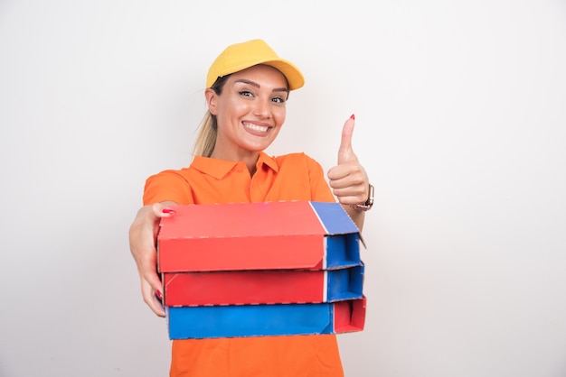 Repartidor sonriente sosteniendo cajas de pizza haciendo pulgares.