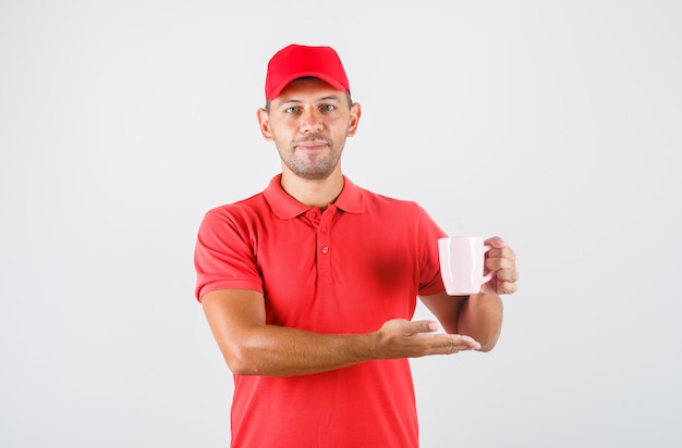 Repartidor en uniforme rojo sosteniendo una taza de bebida y sonriendo