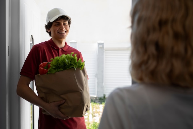 Foto gratuita repartidor de vista lateral con comestibles