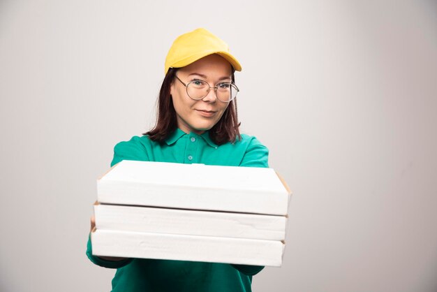 Repartidora dando cartones de pizza sobre un fondo blanco. Foto de alta calidad