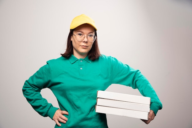 Repartidora llevando cartones de pizza sobre un fondo blanco. Foto de alta calidad