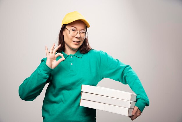 Repartidora llevando cartones de pizza sobre un fondo blanco. Foto de alta calidad