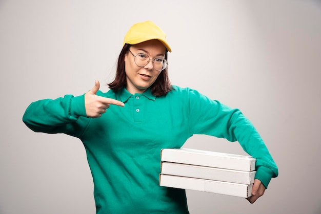 Repartidora mostrando cartones de pizza sobre un fondo blanco. Foto de alta calidad