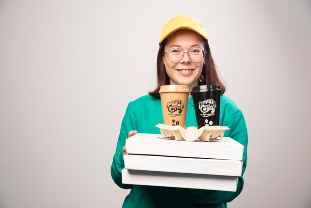 Repartidora ofreciendo cartón de tazas de café sobre un fondo blanco. Foto de alta calidad