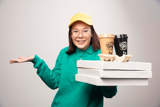 Repartidora sosteniendo cartón de tazas de café sobre un fondo blanco. Foto de alta calidad