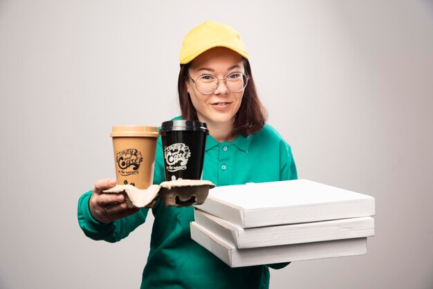 Repartidora sosteniendo cartón de tazas de café sobre un fondo blanco. Foto de alta calidad