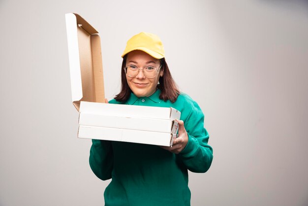 Repartidora sosteniendo cartones de pizza sobre un fondo blanco. Foto de alta calidad
