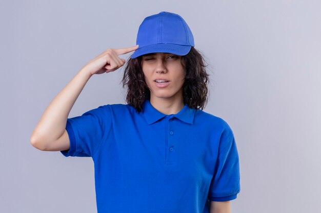 Repartidora en uniforme azul y gorra señalando la sien con el dedo, pensando, centrado en una tarea de pie en blanco