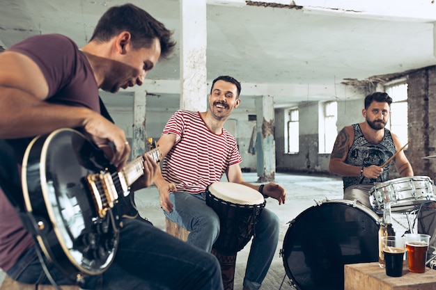 Foto gratuita repetición de la banda de música rock. bajista, guitarrista eléctrico y baterista en loft.