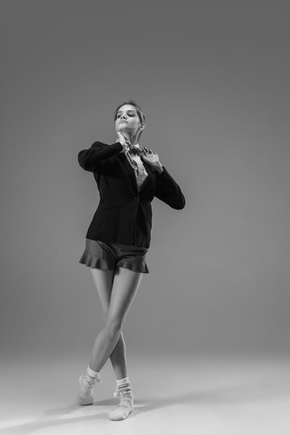 Reporte. Joven mujer de moda y elegante con chaqueta y calcetines trabajando desde casa. Mitad de estilo comercial y mitad hogareño. En blanco y negro.