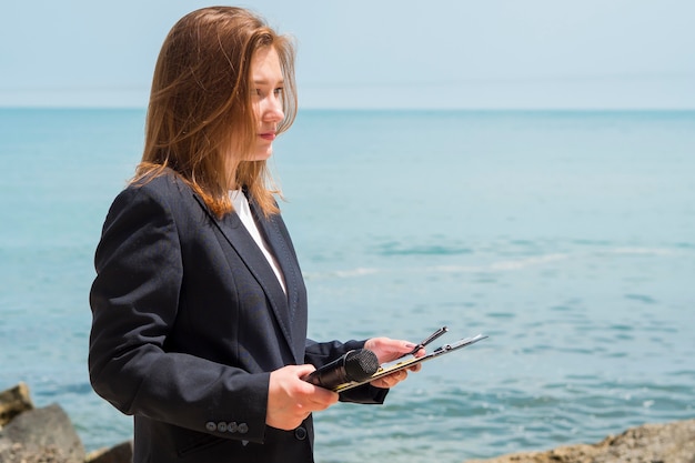 Reportero con libreta junto al mar