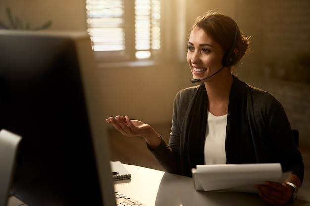 Representante de servicio al cliente feliz usando computadora mientras se comunica con clientes en línea