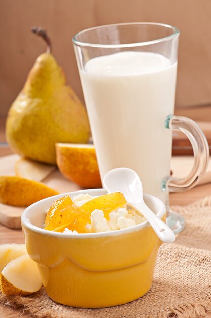 Requesón con mermelada de pera en un tazón y un vaso de leche