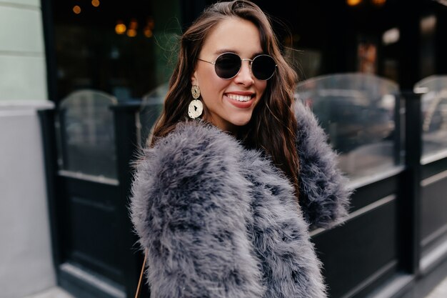 Resistente chica de cabello oscuro caminando en la ciudad en la mañana de otoño.