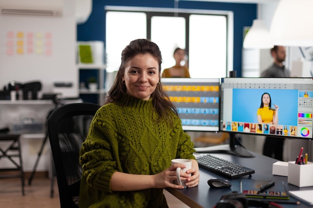 Foto gratuita retocador de mujer mirando a la cámara sonriendo sentado en la agencia de medios de diseño creativo