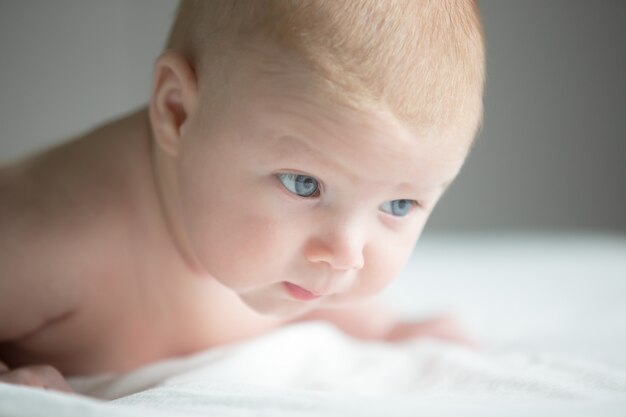 Retrato de 3 meses recién nacido tratando de gatear, mantenga la cabeza hacia arriba