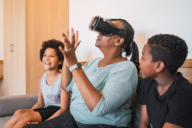 Retrato de abuela afroamericana y nietos jugando junto con gafas VR en casa