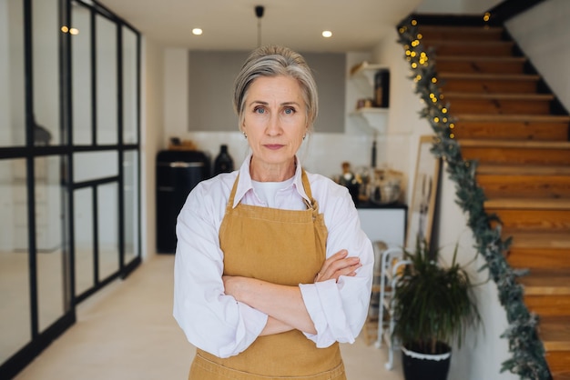 Retrato de una abuela estricta parada en una pose disgustada mirando enojada a la cámara