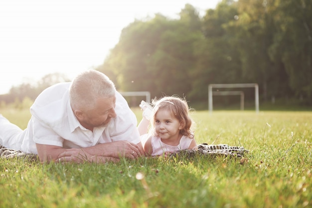 Retrato de abuelo con nieta, relajarse juntos en el parque