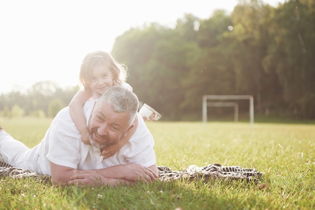 Retrato de abuelo con nieta, relajarse juntos en el parque