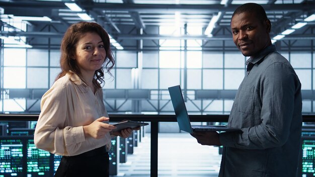Retrato de administradores de sistemas felices en el centro de datos que utilizan dispositivos