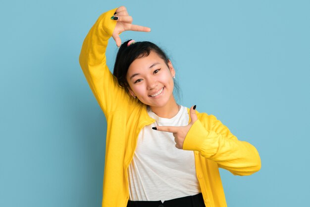 Retrato de adolescente asiático aislado sobre fondo azul studio