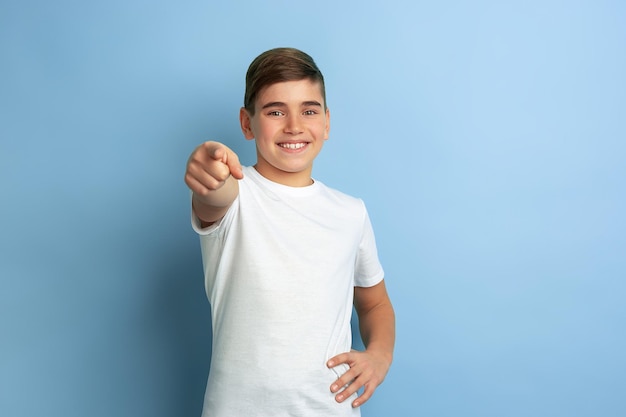 Retrato de adolescente caucásico aislado en la pared azul del estudio