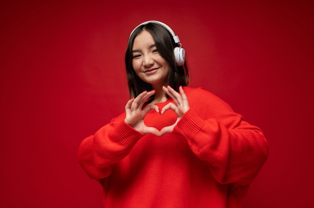 Foto gratuita retrato de una adolescente escuchando música y mostrando las manos del corazón