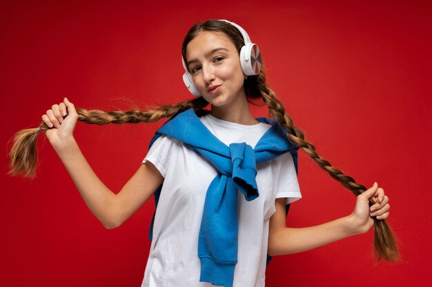 Retrato de una adolescente escuchando música y sosteniendo sus coletas