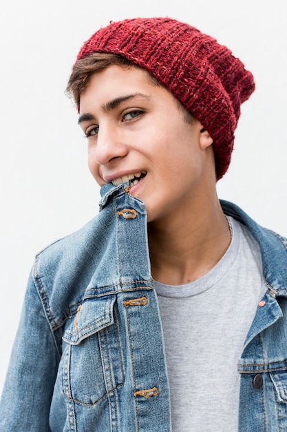 Retrato de adolescente con estilo con cuello de camisa de mezclilla en la boca contra el fondo blanco