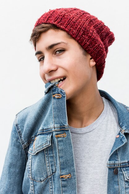 Retrato de adolescente con estilo con cuello de camisa de mezclilla en la boca contra el fondo blanco