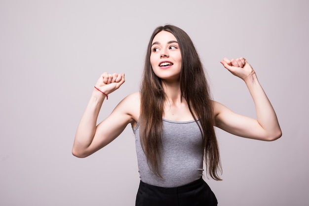 Retrato de una adolescente feliz alegre vestida con chaqueta de mezclilla celebrando el éxito mientras baila aislado