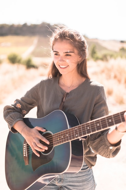 Retrato de una adolescente feliz tocando la guitarra