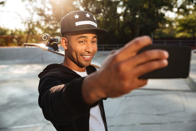 Retrato de un adolescente masculino africano sonriente tomando un selfie