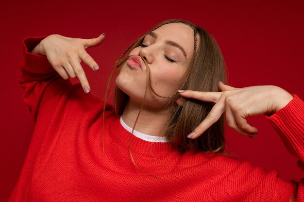 Retrato de una adolescente mostrando el signo de la paz y manteniendo un bigote falso hecho de su cabello en la cara