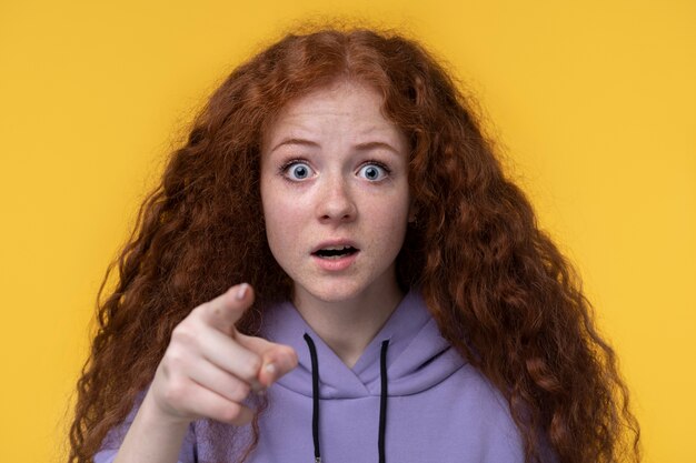 Foto gratuita retrato de una adolescente que parece sorprendida y señala algo