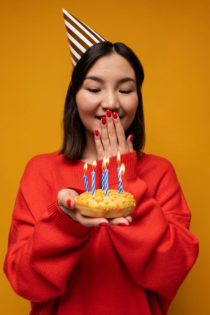 Retrato de una adolescente sosteniendo una dona con velas de cumpleaños y mirando sorprendido