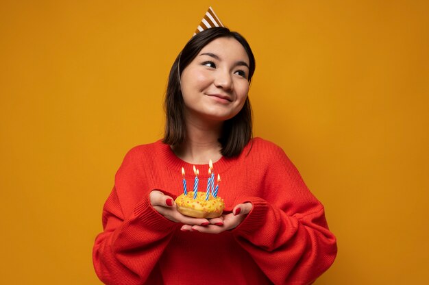 Retrato de una adolescente sosteniendo una dona con velas de cumpleaños