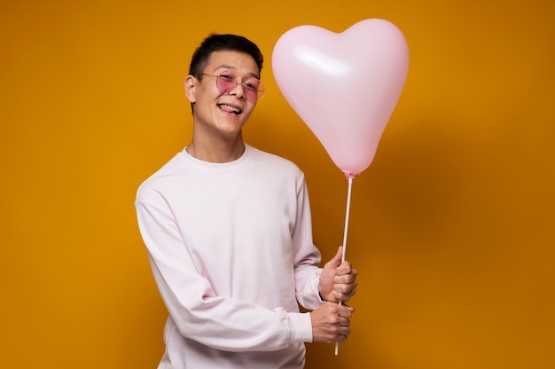 Retrato de un adolescente sosteniendo un globo en forma de corazón y sacando la lengua