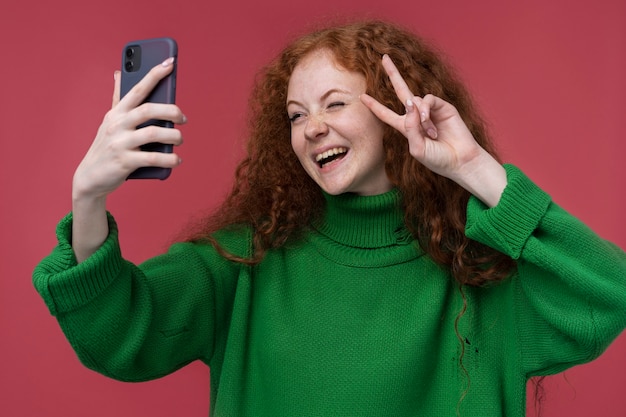 Retrato de una adolescente tomando un selfie y mostrando el signo de la paz