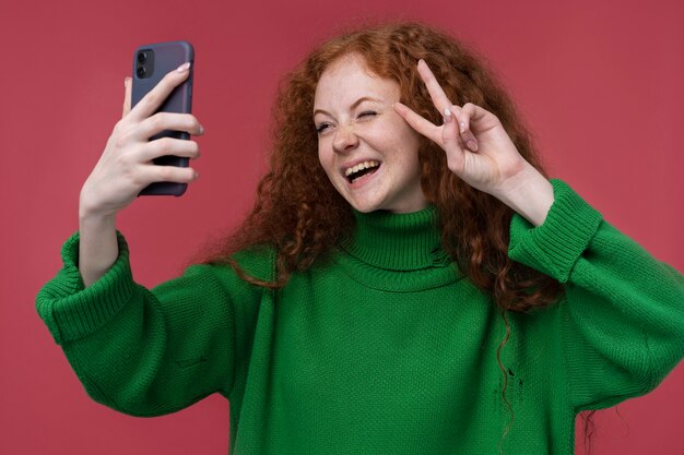 Retrato de una adolescente tomando un selfie y mostrando el signo de la paz