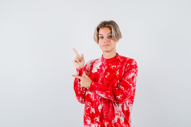 Retrato de adolescente varón rubio apuntando a la esquina superior izquierda en camisa de gran tamaño y mirando triste vista frontal